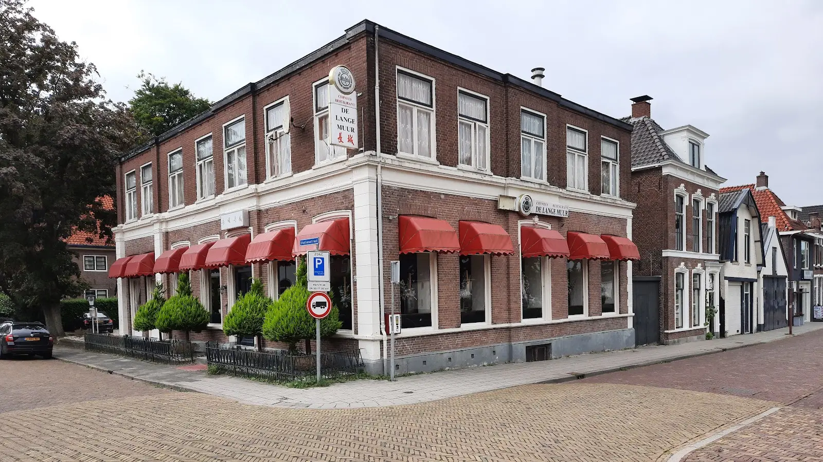 Het pand van De Lange Muur met rode markiezen op de hoek van de Stationsstraat
