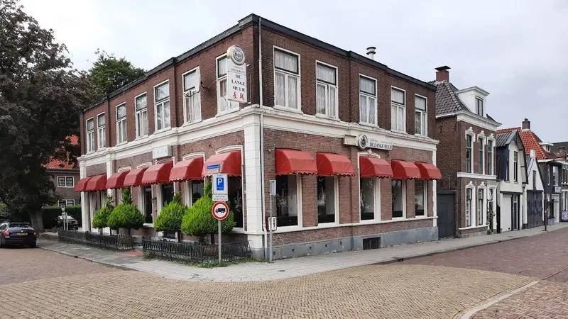 Het pand van De Lange Muur met rode markiezen op de hoek van de Stationsstraat